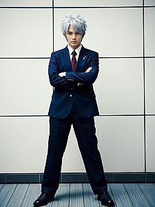 Confident Man in Navy Business Suit with Silver Hair Standing Against Tiled Wall