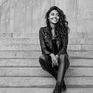Smiling Woman in Leather Jacket on Concrete Stairs