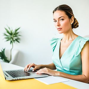 Young Woman in Mint Green Dress Working on Laptop