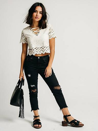 Woman in Boho Chic Ivory Lace Crop Top with Distressed Black Jeans and Black Sandals