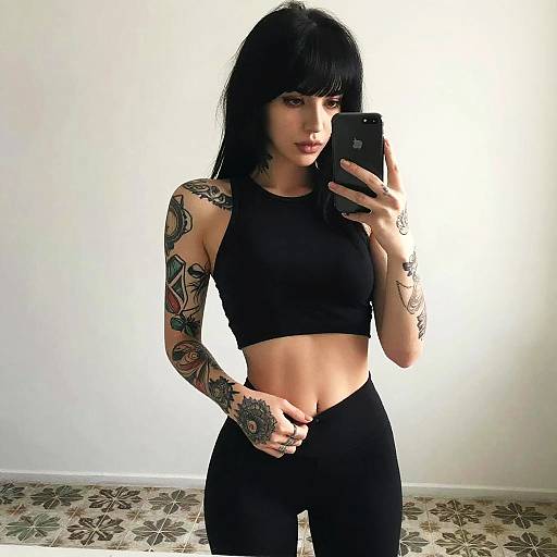 Tattooed Woman in Black Crop Top Taking Mirror Selfie indoors