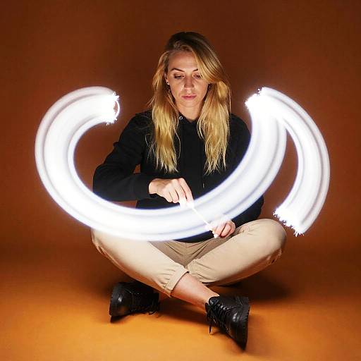 Woman Creating Light Trails With Sparklers on Brown Background