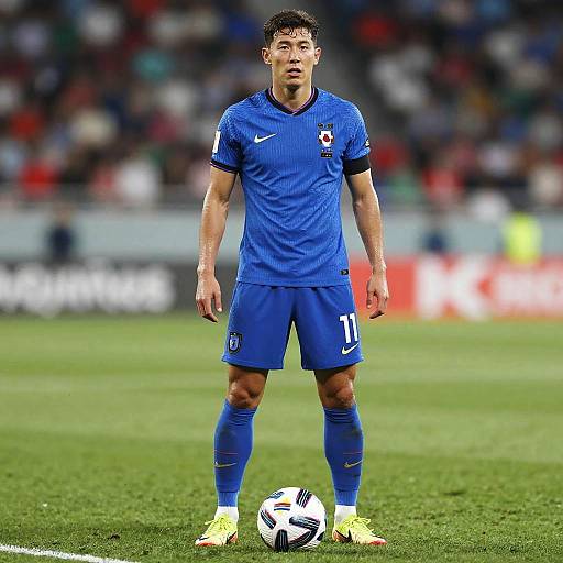 Male Soccer Player in Blue Jersey Preparing for Kick on Football Field