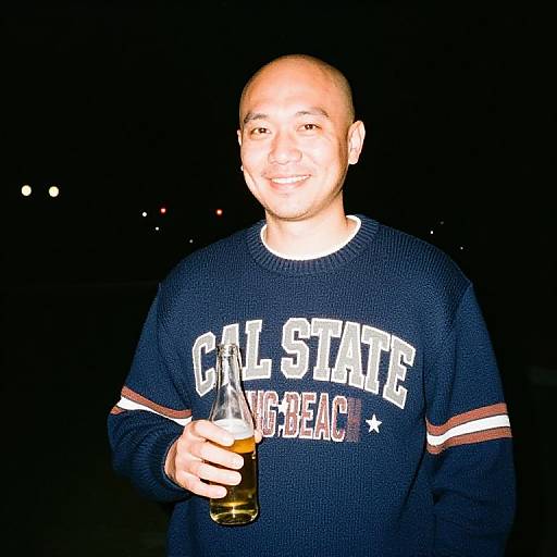 Smiling Man in Cal State Long Beach Sweater Holding Beer Bottle at Night