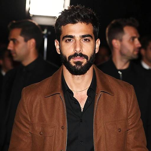 Bearded Young Man in Brown Jacket at Nighttime Event