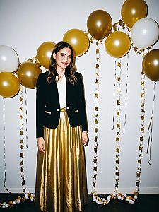 Elegant Woman in Black Blazer and Gold Skirt with Festive Balloon Decoration
