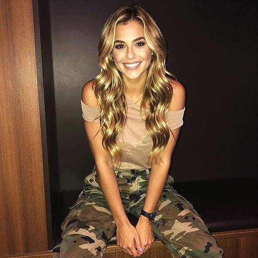 Smiling Woman in Off-Shoulder Top and Camouflage Pants Sitting Indoors