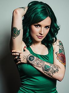 Confident Woman with Green Hair and Vibrant Tattoos in Green Top