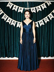 Elegant Woman in Blue Satin Gown at Birthday Celebration