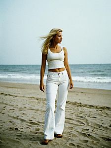 Woman in White Tank Top and Pants Walking on the Beach