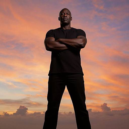 Confident Man Standing Against Vibrant Sunset Sky in Black Clothing