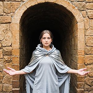 Serene Woman in Stone Archway with Silver Cape