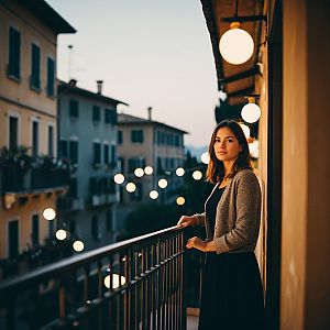 Young Woman on Balcony at Dusk with Warm Street Lamps in European Town