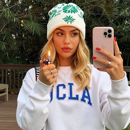 Woman Taking Selfie with Lighter Wearing UCLA Sweatshirt and Palm Tree Beanie