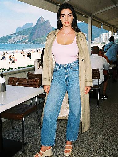 Lean Woman in Technicolor Analog Film Style Wearing Beige Trench Coat and Jeans at Beach Cafe