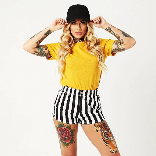 Tattooed Woman in Yellow Shirt and Striped Shorts Wearing Black Cap